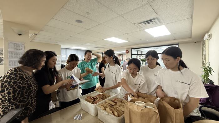 The community hall during a meal service, volunteers and neighbours around tables of packed meals.